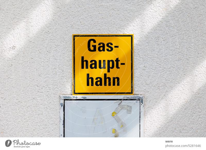 Ein gelbes Schild an einer Hauswand mit dem deutschen Text Gas-haupt-hahn Deutscher Text Main Absperrventil Gefahr Notfall Feuerwehr Gasexplosion Gasaustritt