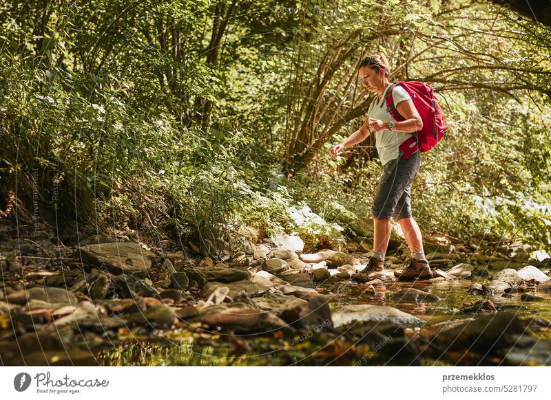 Reisen mit Rucksack Konzeptbild. Backpacker weiblich in Trekking-Stiefel überqueren Berg Fluss. Sommerurlaub Reise Abenteuer reisen Ausflug Urlaub