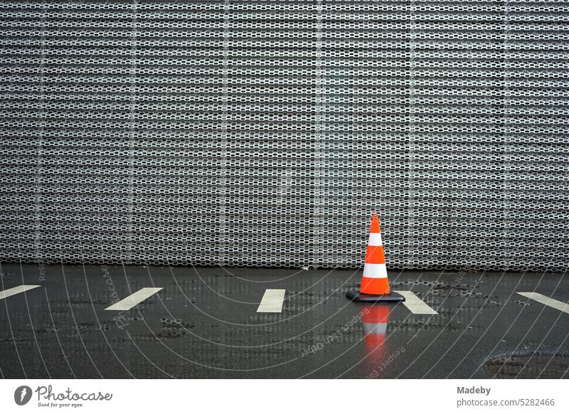Lübecker Hütchen, Pylon oder Verkehrsleitkegel bei Regen auf nassem Asphalt vor der Fassade aus Stahlblech eines modernen Autohaus in der Hanauer Landstraße im Ostend von Frankfurt am Main
