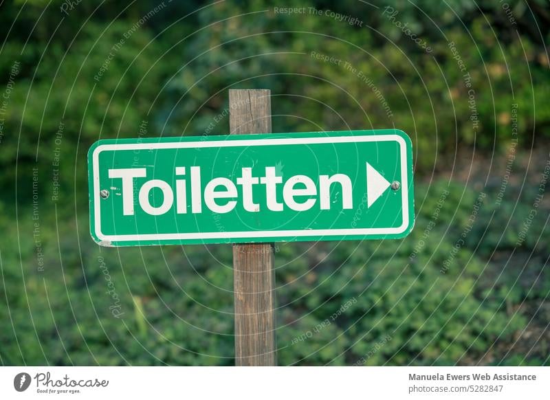 Ein Hinweisschild, das auf die nächste Toilette hinweist beschilderung toilette wc finden notdurft wegweiser öffentlich öffentliche toiletten unterwegs
