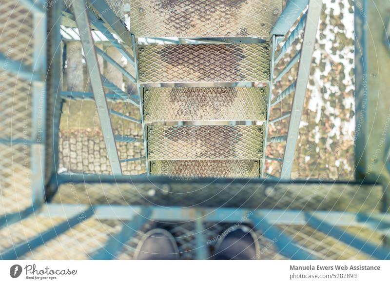 Ein Blick nach unten auf den Treppengang eines metallenen Aussichtsturms treppe stufen treppenstufen gerüst draußen outdoor kletterturm aussichtsturm blech