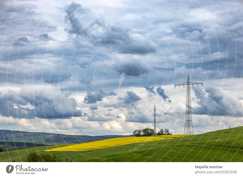 Strommast vor bewölktem Himmel Wolken bewölkter himmel Feld Felder Raps Rapsfeld Landwirtschaft ökostrom Energie Wind dramatischer himmel