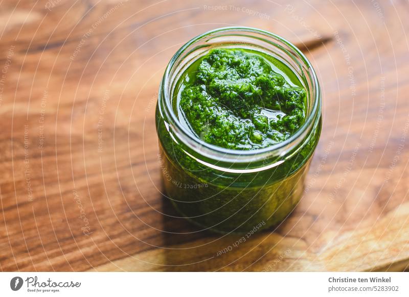 Ein Glas selbstgemachtes Bärlauchpesto steht auf einer Holzplatte Bärlauch-Pesto Vorrat Lebensmittel Vegetarische Ernährung Bioprodukte Kräuter & Gewürze