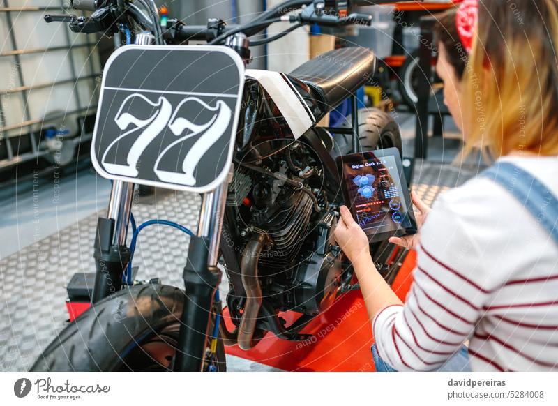 Mechanikerin nutzt Diagnose-App, um individuelles Motorrad zu überprüfen unkenntlich Frau benutzend Diagnostik Anwendung Tablette digital überblicken