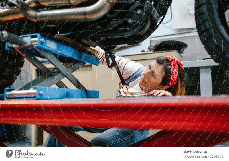 Mechanikerin überprüft Motorrad auf der Plattform Arbeiter Frau Überprüfung überblicken arbeiten Reparatur Fabrik Garage Werkstatt Podest Besichtigung