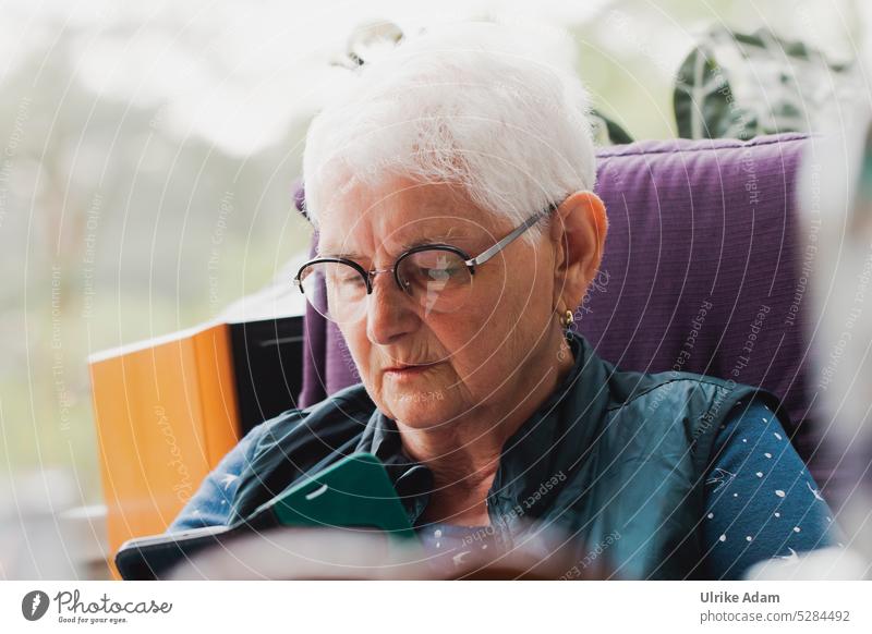 MainFux | Immer auf dem Laufenden - Frau liest am Smartphone lesen konzentriert Brille graues Haar Rentnerin Senior selbstbewusst Nachrichten Handy