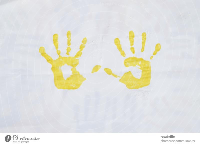 gelber Abdruck zweier Kinderhände Hand Hände Farbe Fingerfarbe Handabdruck Spiel malen Kunst Kreativität Fingerabdruck Handfläche berühren Spuren Kindheit