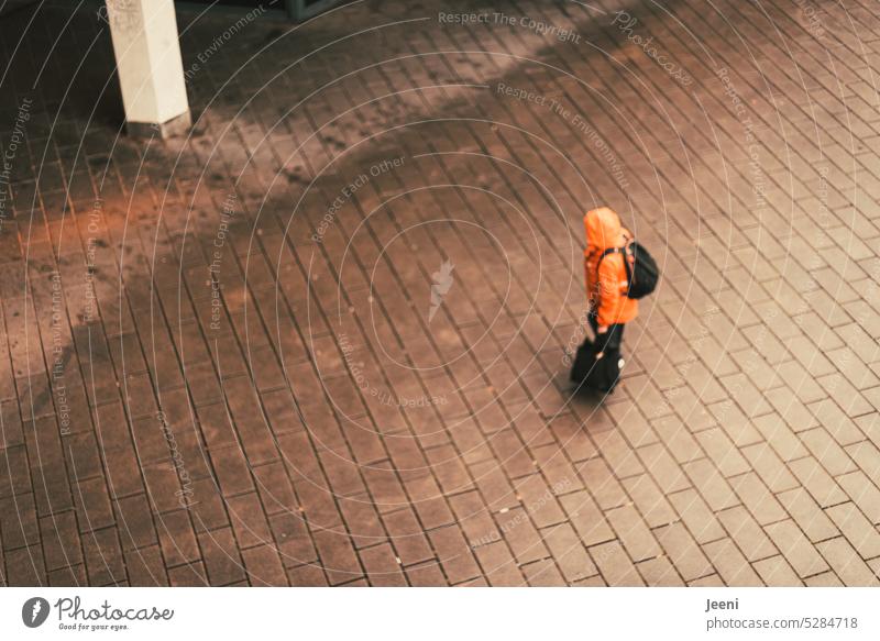 Auf dem Weg nach… gehen Mensch von oben Vogelperspektive orange Regen Regenjacke Gepäck Rucksack Tasche tragen lebensweg Richtung Ziel zielstrebig Orientierung