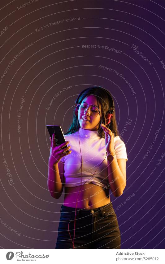 Frau mit Kopfhörern und Smartphone benutzend zuhören Musik Apparatur modern Browsen Surfen soziale Netzwerke Stil trendy Gerät jung Outfit Mobile Telefon Gesang