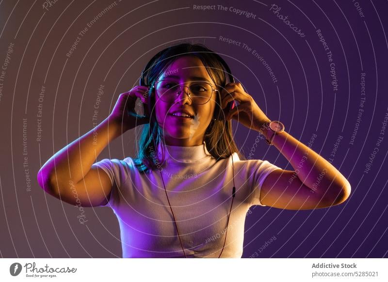 Junge Frau trägt Kopfhörer beim Musikhören zuhören Lächeln selbstbewusst jung Apparatur froh meloman modern Gesang Melodie cool Individualität pulsierend