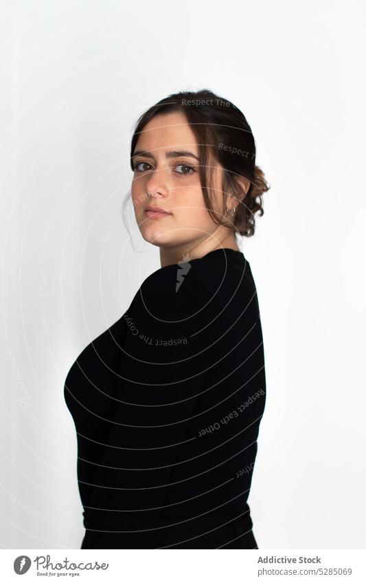 Frau in schwarzem Outfit steht in der Nähe einer weißen Wand emotionslos Teint einfach Profil Windstille ernst Frisur Pullover Vorschein nachdenklich jung