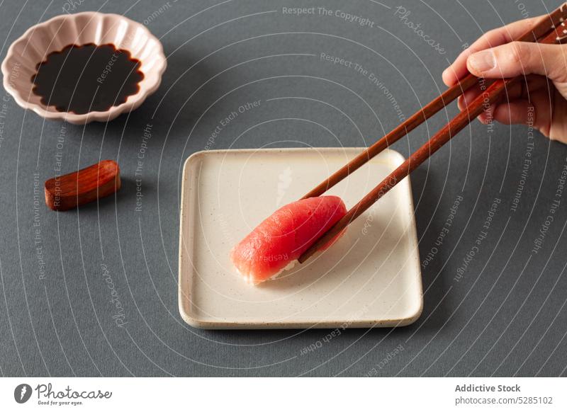 Person mit Essstäbchen, die Sashimi-Sushi isst Hand Teller Sojasauce Asiatische Küche dienen Orientalisch Lebensmittel Restaurant Fisch Lachs handgefertigt