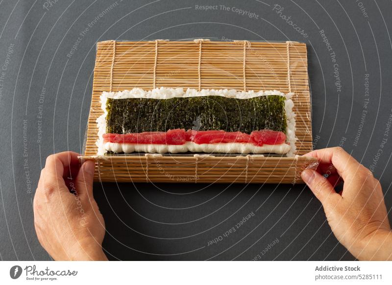 Person, die Maki-Sushi rollt Hand maki rollen Seegras Reis Lachs Asiatische Küche Unterlage Lebensmittel Gesundheit Fisch geschmackvoll Bambus Tradition