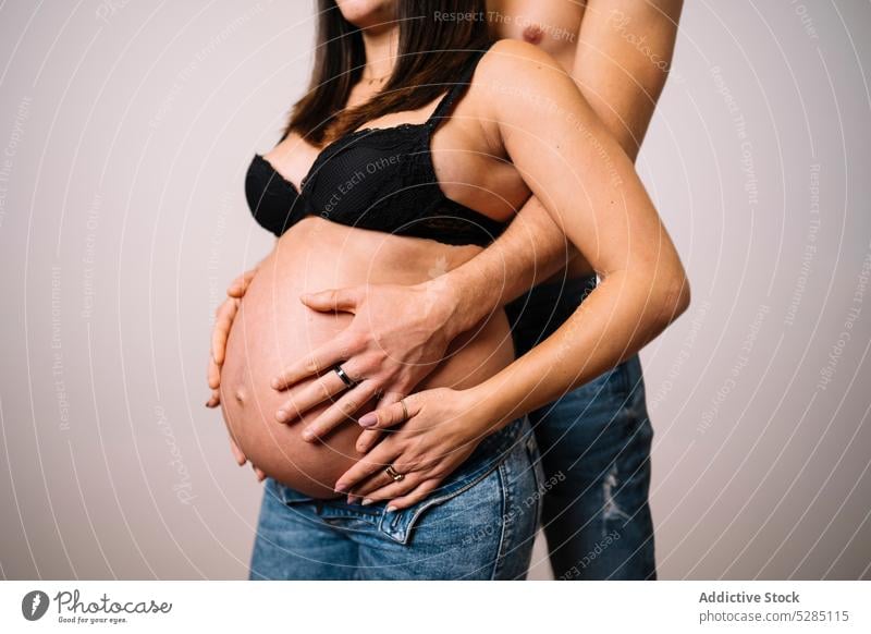 Crop Mann umarmt schwangere Frau mit nacktem Bauch Paar Umarmung Bauch anfassen Umarmen warten Liebe Pflege erwarten unverhüllt friedlich jung Harmonie sanft
