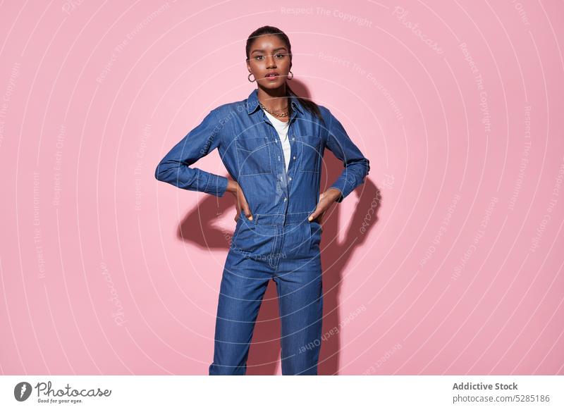 Selbstbewusste schwarze Frau in Jeans-Outfit schaut in die Kamera im Studio selbstbewusst ernst Hand auf der Taille Model Körperhaltung Jeansstoff