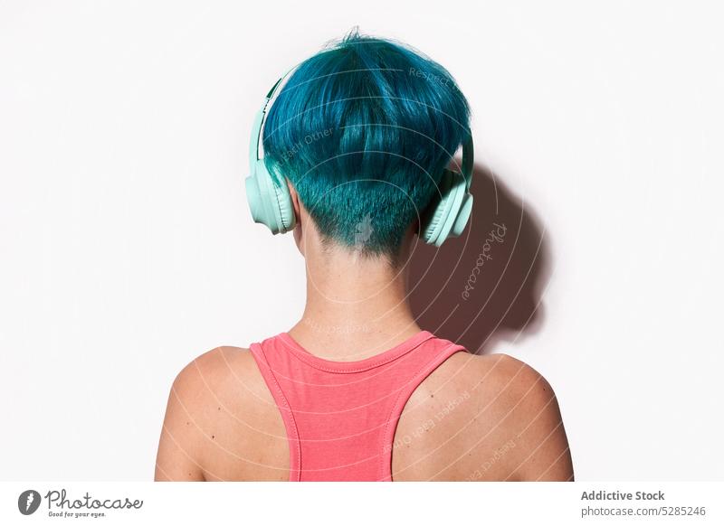 Anonyme Frau, die mit Kopfhörern vor weißem Hintergrund Musik hört meloman zuhören unterhalten Studioaufnahme Hobby Schatten Freude jung Klang Kurze Haare Audio