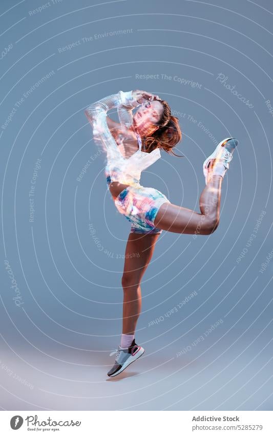 Fitte Frau tanzt im Studio Tanzen springen Energie Arme hochgezogen ausführen Projektor Licht sich[Akk] bewegen aktiv Studioaufnahme passen sportlich perfekt
