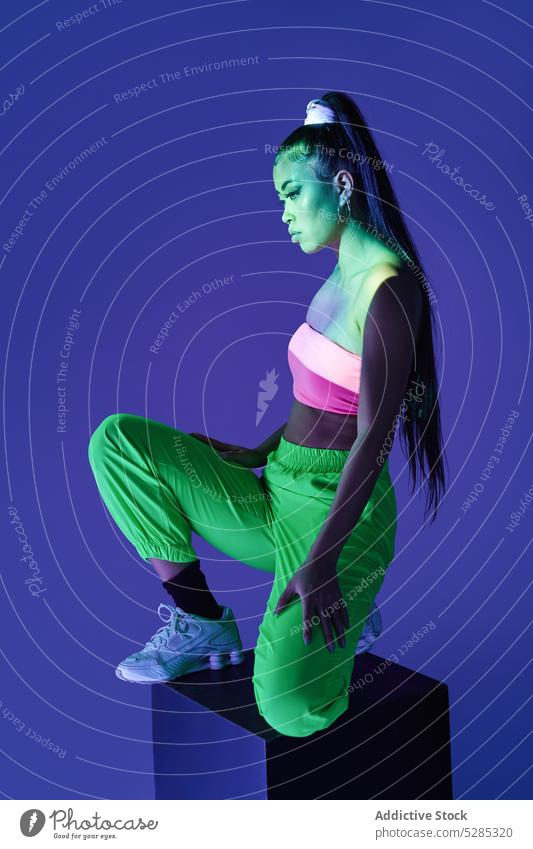 Junge gemischtrassige Frau steht auf einem Würfel Projektor Körperhaltung Studioaufnahme Figur Vorschein Persönlichkeit Individualität leuchten Dame jung
