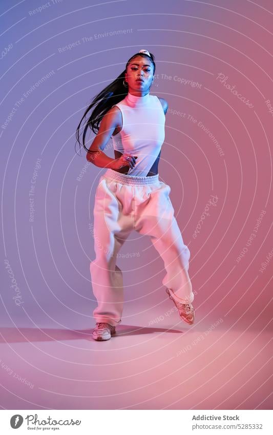 Energetische gemischtrassige Frau tanzt im Studio mit Neon-Beleuchtung Tänzer Fähigkeit üben Aktion Tanzen Studioaufnahme Dame jung gemischte Rasse ethnisch
