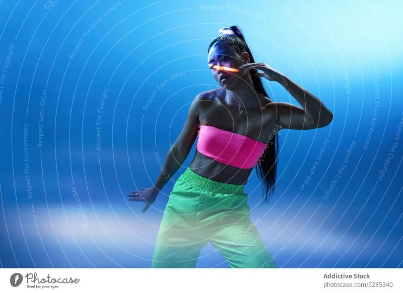 Gemischtrassige Frau tanzt in einem Studio mit blauer Neon-Beleuchtung Tänzer üben Aktion Projektor ausführen Tanzen Studioaufnahme Hobby aktiv Dame jung