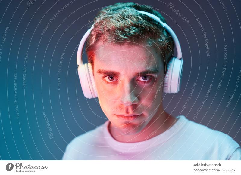 Mann hört Musik mit Kopfhörern zuhören neonfarbig sich[Akk] entspannen Drahtlos Windstille leuchten Porträt männlich jung Klang Gesang modern Audio lässig