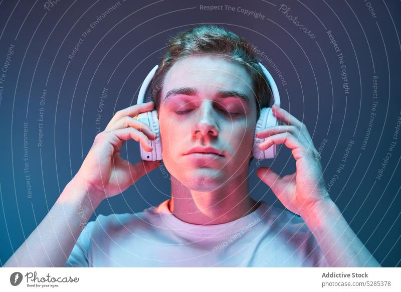 Mann hört Musik mit Kopfhörern zuhören neonfarbig sich[Akk] entspannen Drahtlos Windstille leuchten Augen geschlossen männlich jung Klang Gesang modern Audio