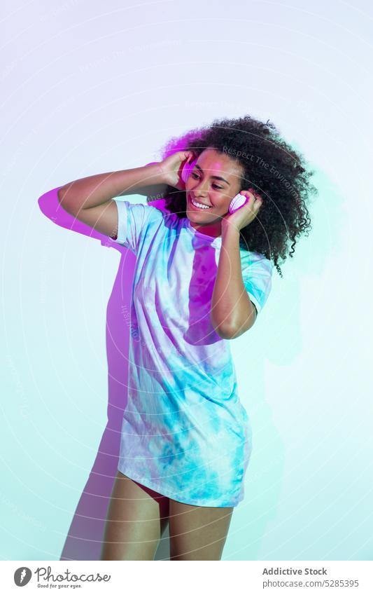 Glückliche schwarze Frau tanzt im Studio Tanzen Lächeln heiter Stil neonfarbig Kopfhörer Musik positiv jung krause Haare ethnisch Afroamerikaner trendy Party