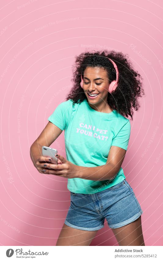 Erfreute schwarze Frau macht Selfie mit Smartphone Musik zuhören Kopfhörer Lächeln Glück heiter Augen geschlossen Afroamerikaner jung ethnisch Gerät Apparatur