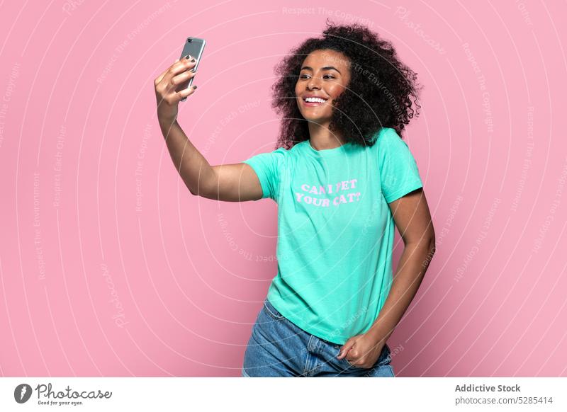 Erfreute schwarze Frau macht Selfie mit Smartphone Musik zuhören Kopfhörer Lächeln Glück heiter Augen geschlossen Afroamerikaner jung ethnisch Gerät Apparatur