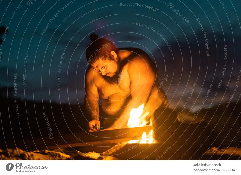 Fettleibiger Mann bereitet sich auf ein brennendes Feuer vor Freudenfeuer ohne Hemd Strand Nacht fettleibig vorbereiten sich[Akk] entspannen Küste Ufer Himmel