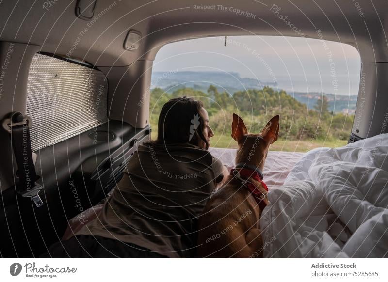 Frau und Hund auf Matratze im Auto liegend Reisender Haustier sich[Akk] entspannen ruhen bewundern Landschaft PKW Urlaub malerisch Lügen gehorsam Tier