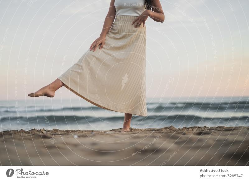 Anonyme unbekümmerte junge hispanische Frau, die am Meeresufer in den Sand tritt Strand Bein angehoben genießen Urlaub Sonnenuntergang Tourist Glück MEER