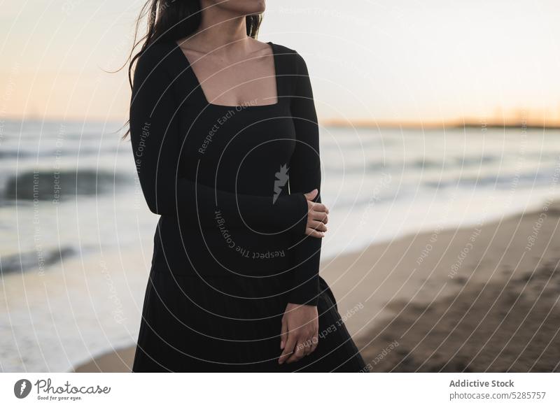 Selbstsichere anonyme ethnische Dame am sandigen Meeresufer Frau Strand Tourist Sonnenuntergang MEER Urlaub selbstbewusst feminin jung hispanisch brünett Kleid
