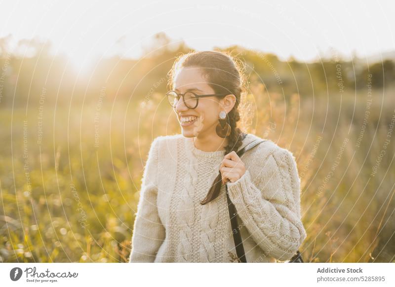Fröhliche Frau genießt die Zeit auf dem Lande Lächeln Haare berühren Sonnenuntergang Landschaft Feld Natur Glück heiter sich[Akk] entspannen jung Brille Freude