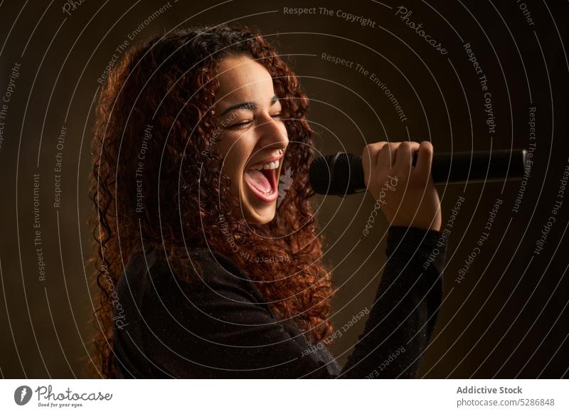 Professionelle Sängerin mit Mikrofon Frau singen Gesang ausführen Stimme Musik Probe Aufzeichnen jung krause Haare Musiker Talent Klang Fähigkeit Audio Atelier