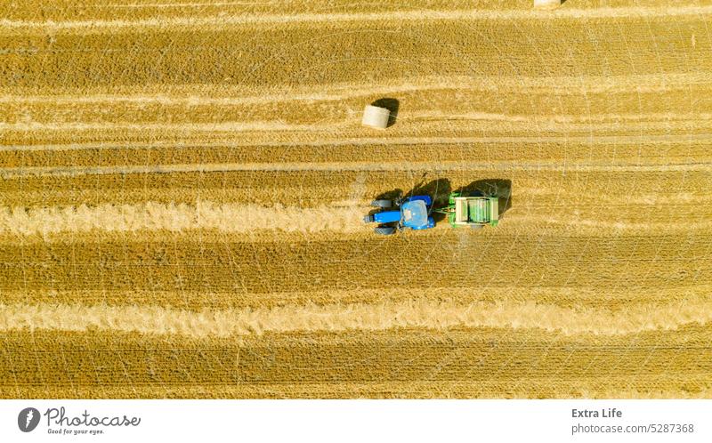 Luftaufnahme einer vom Traktor gezogenen Ballenmaschine zum Einsammeln von Stroh vom abgeernteten Feld oben Antenne landwirtschaftlich Ackerbau anbaufähig