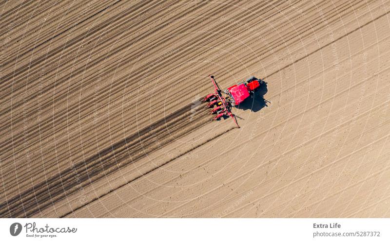 Luftaufnahme eines Traktors, der eine Sämaschine über ein landwirtschaftliches Feld zieht, Ackerland oben Ackerbau anbaufähig Müsli Mais Kornfeld Land Ernte