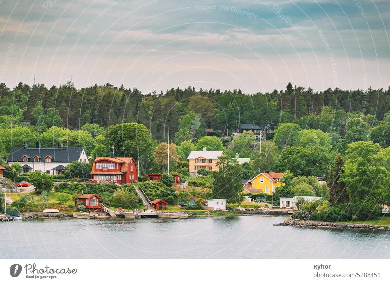 Schweden. Schöne rote und gelbe schwedische Holzblockhäuser Häuser auf felsigen Insel Küste im Sommer Abend. See oder Fluss Landschaft. Haus Hütten Hygge reisen