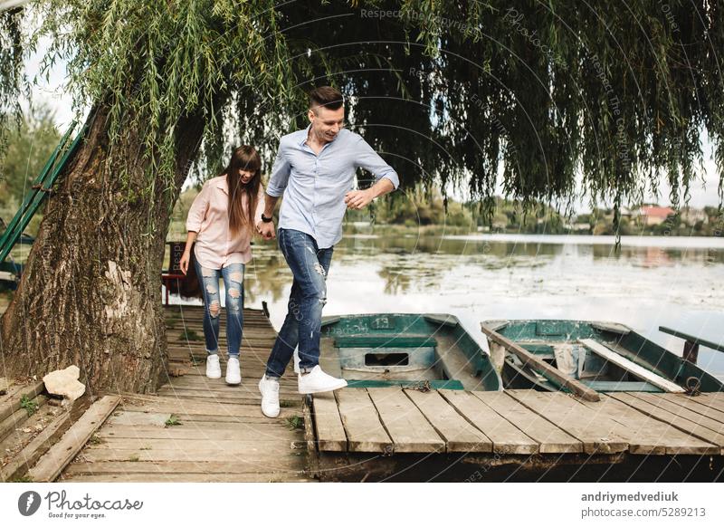Glückliches junges Paar im Freien. Junges Liebespaar läuft händchenhaltend über eine Holzbrücke. Freund reisen Freundin Sommer Fröhlichkeit Natur flirten Spaß