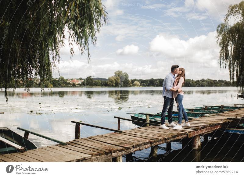Junge romantische Paar hat Spaß im Sommer sonnigen Tag in der Nähe des Sees. Genießen Sie die Zeit zusammen im Urlaub. Mann und Frau sind umarmt und küssen.
