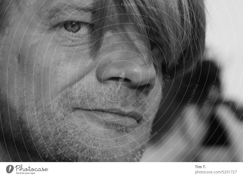 ein Mann mit Haaren im Gesicht sieht in die Kamera Haare & Frisuren Auge Dreitagebart s/w bnw Schwarzweißfoto Tag Außenaufnahme Berlin Stadtzentrum Hauptstadt