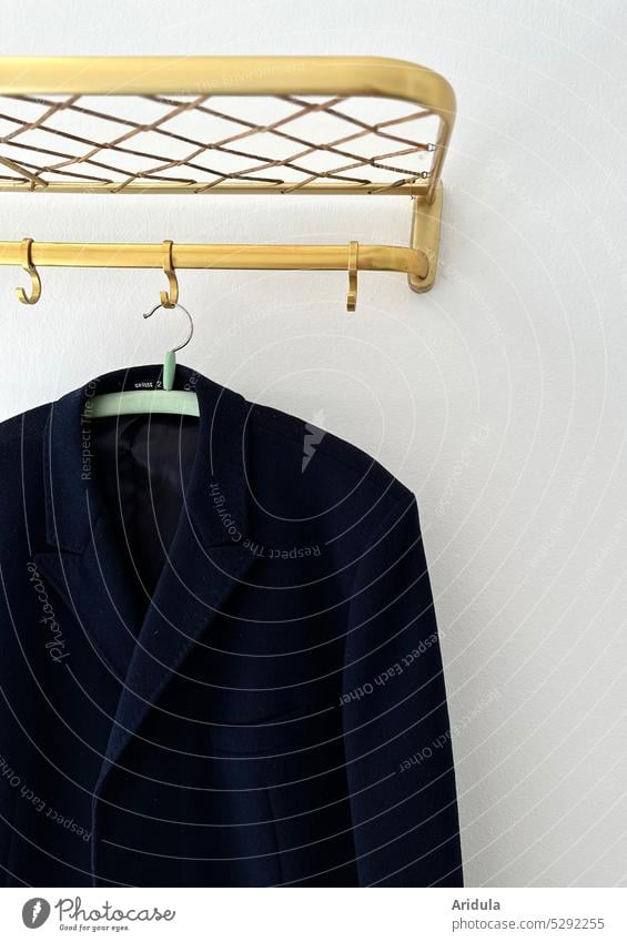 Dunkler Mantel hängt an goldener Garderobe 50's 50er Haken aufhängen Ordnung Nostalgie Bekleidung Wand Kleiderbügel Kleiderhaken Mode nostalgisch retro interior
