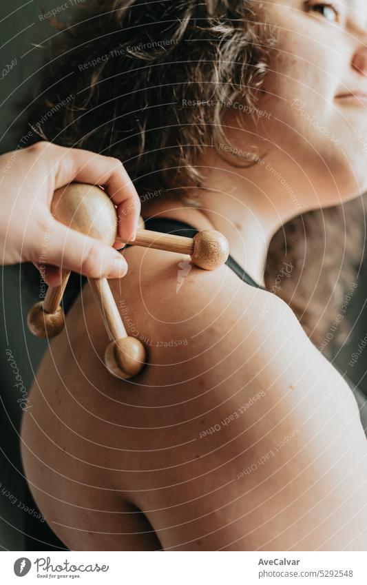 Hand holing eine Rolle hölzerne Haut Massagegerät in den Rücken des Modells. Madero Therapie Massage mit hölzernen Nudelholz, um die Blutzirkulation zu stimulieren.