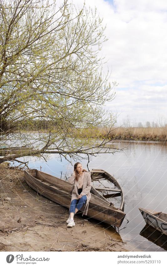 schöne junge Frau sitzt in einem Boot in der Nähe des Flusses an einem Frühlingstag und hat Spaß. Hintergrund Menschen Einsamkeit menschlich Mädchen Landschaft