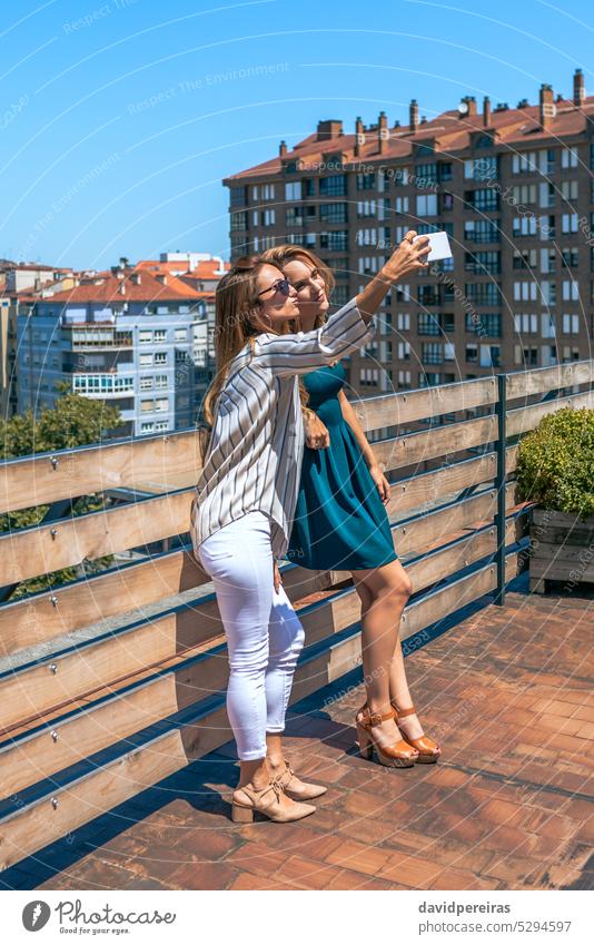 Zwei Freundinnen machen ein Selfie auf einem Dach in der Stadt an einem Sommertag Frau Glück Lächeln unter Foto Dachterrasse Terrasse Porträt Telefon freundlich