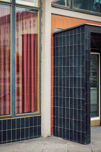 Eingang eines Bauwerks der Nachkriegsmoderne mit schwarzen Fliesen, Fenster, Vorhang Moderne Architektur orange architektur form geometrie Konzertsaal
