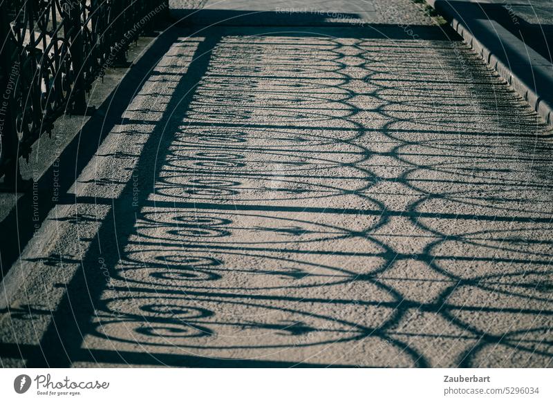 Schattenwurf eines geschmiedeten Geländers auf dem Gehweg einer Brücke Ornament Muster Weg Straße Friedrichstraße Sonne Sonnenschein Berlin Mitte Fußgängerweg