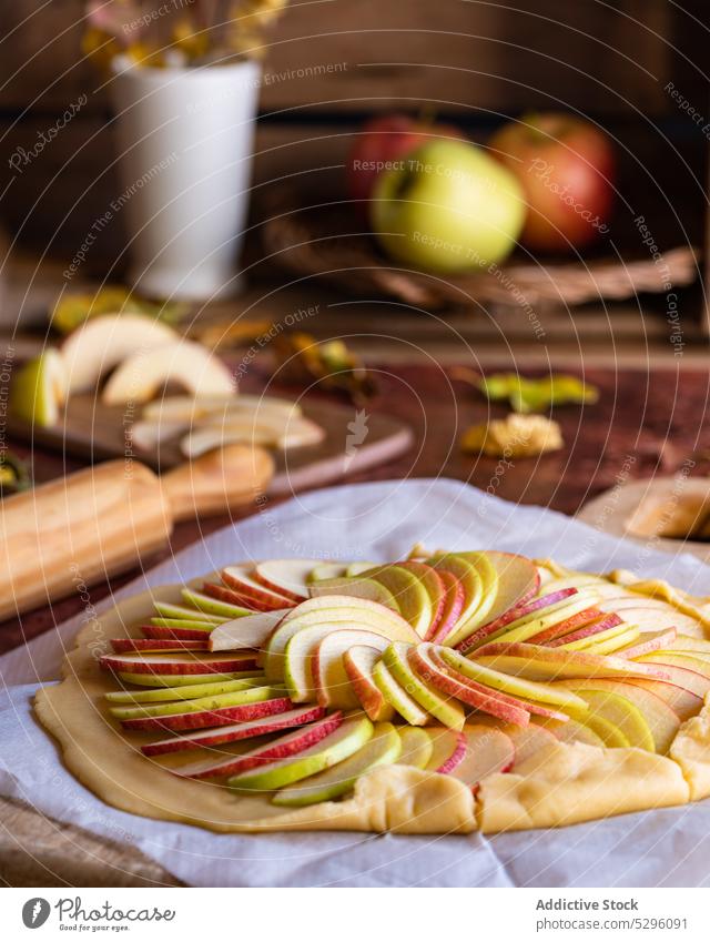 Ungebackener Galette-Apfelkuchen auf Backpapier Pasteten roh Teigwaren ungebacken selbstgemacht vorbereiten Scheibe ungekocht Gebäck Mürbeteig Küche zu Hause