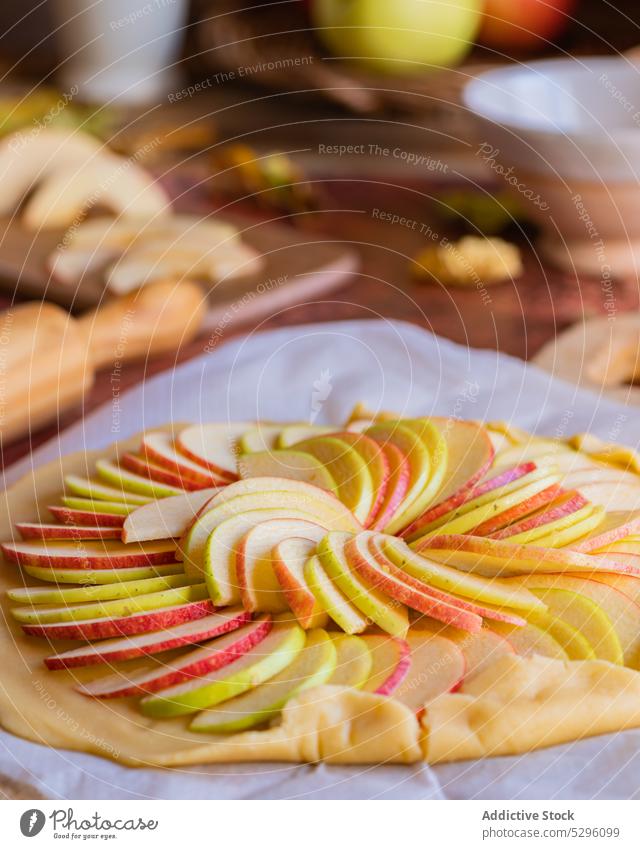 Ungebackener Galette-Apfelkuchen auf Backpapier Pasteten roh Teigwaren ungebacken selbstgemacht vorbereiten Scheibe ungekocht Gebäck Mürbeteig Küche zu Hause
