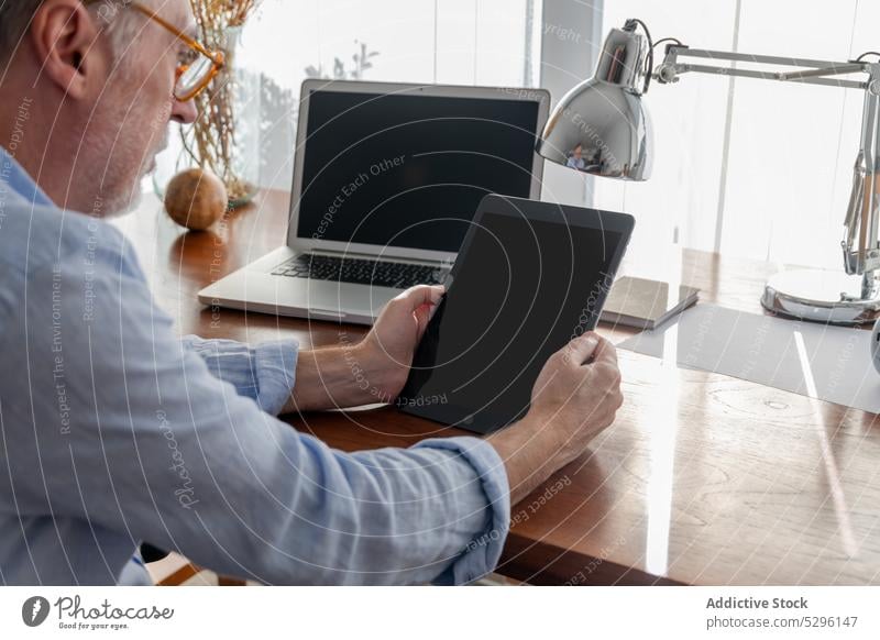 Konzentrierter Mann arbeitet an einem digitalen Tablet freiberuflich benutzend Tablette Laptop Arbeit nachdenken Fokus Konzentration männlich abgelegen Browsen